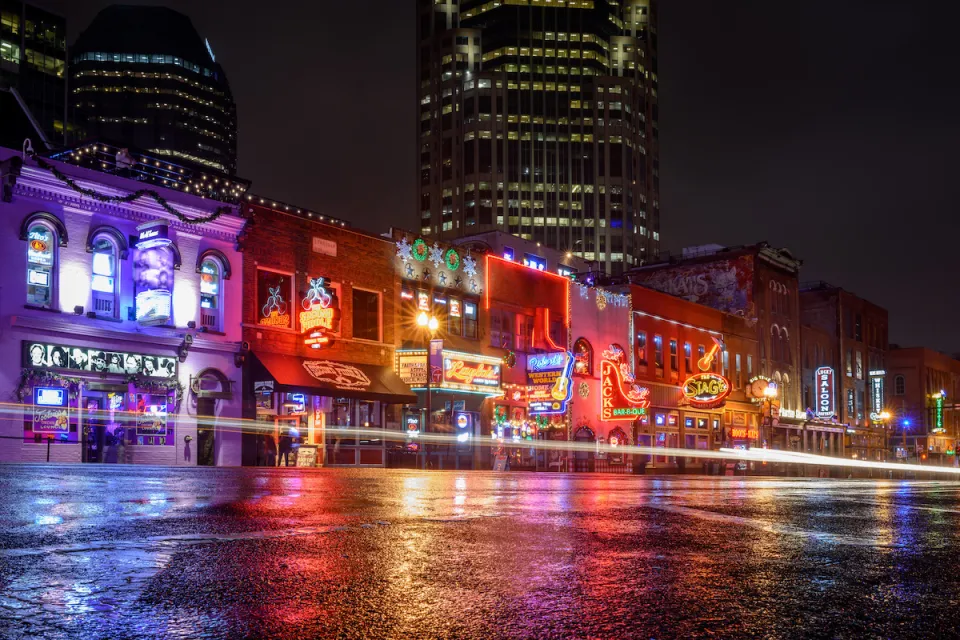 View from street level of brightly neon-lit bars and theaters on Broadway in downtown Nashville, Tennessee.
